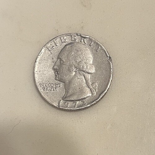 1973 quarter broadstrike error showing coin struck without collar resulting in wider diameter and smooth edge
